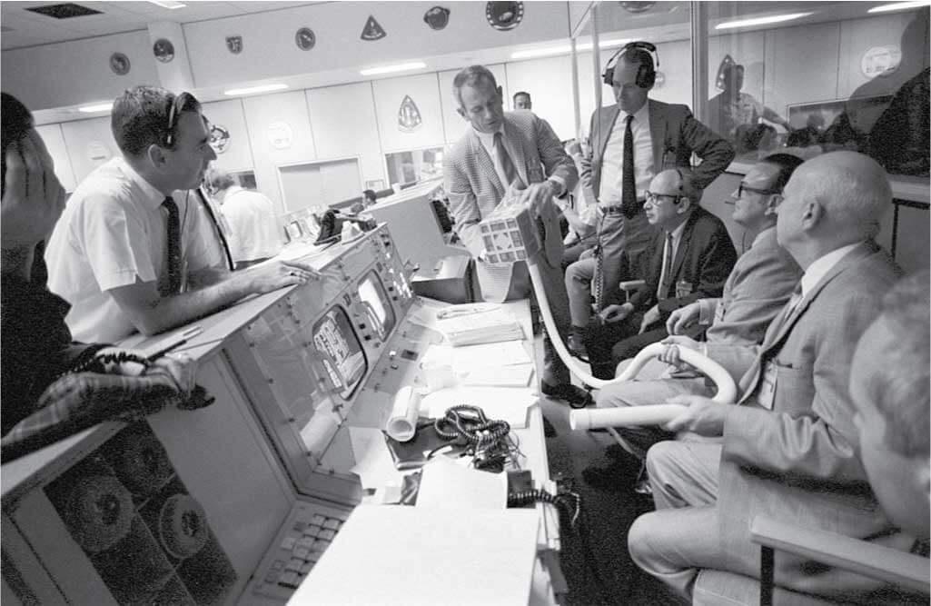 Deke Slayton shows the adapter devised to make use of square Command Module lithium hydroxide canisters to remove excess carbon dioxide from the Apollo 13 LM cabin.