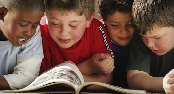 Photo of young school children reading a book together
