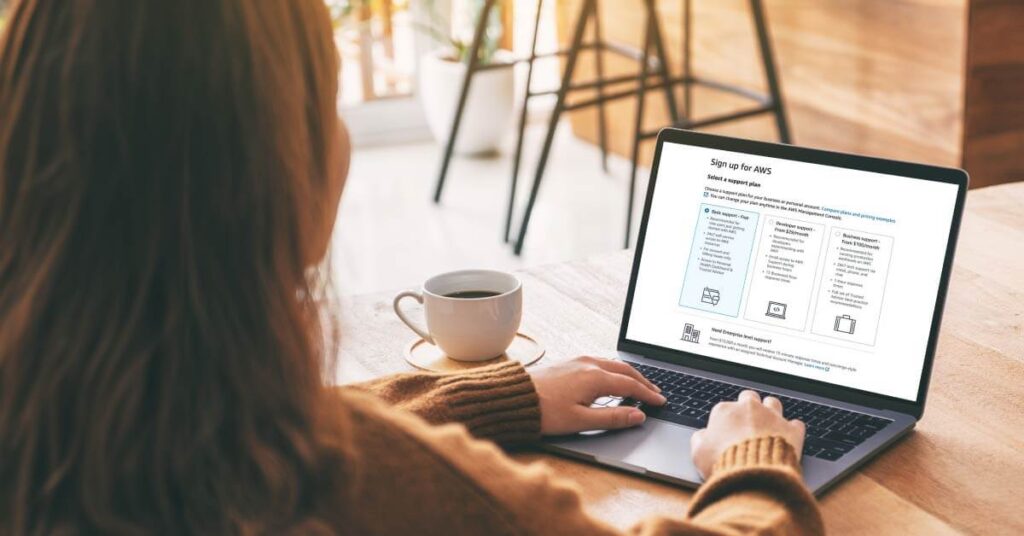 Photo of woman seated at table and with 'SIgn up for AWS' shown on the screen